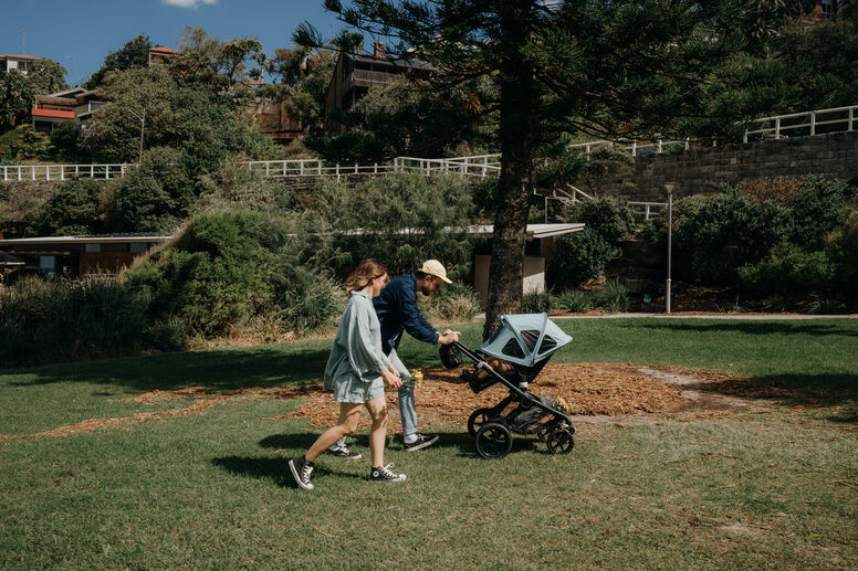 Parents pushing stroller in shade