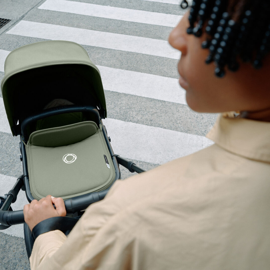 A parent pushing a Bugaboo Fox 5 stroller with one hand.