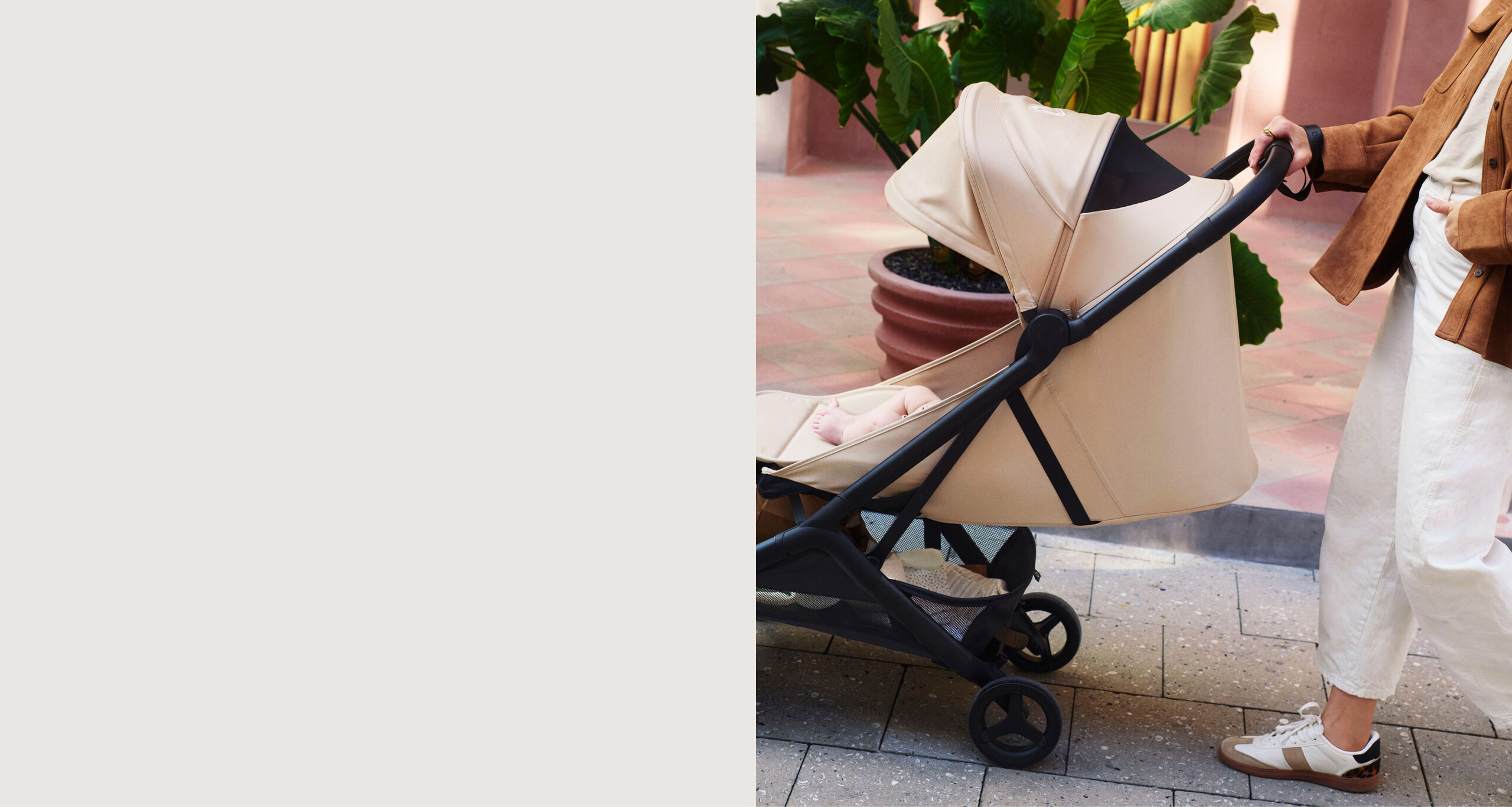 Mom strolls with baby in a Bugaboo Butterfly 2 Plus travel pram in Desert Taupe fabrics. The pram seat lays flat.
