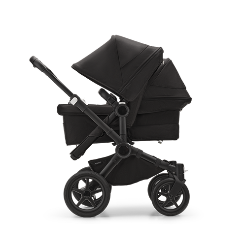 A Bugaboo Fox 5 all-terrain stroller with a bassinet. The fabrics are in Forest Green. The background is reddish with streaks of gold.