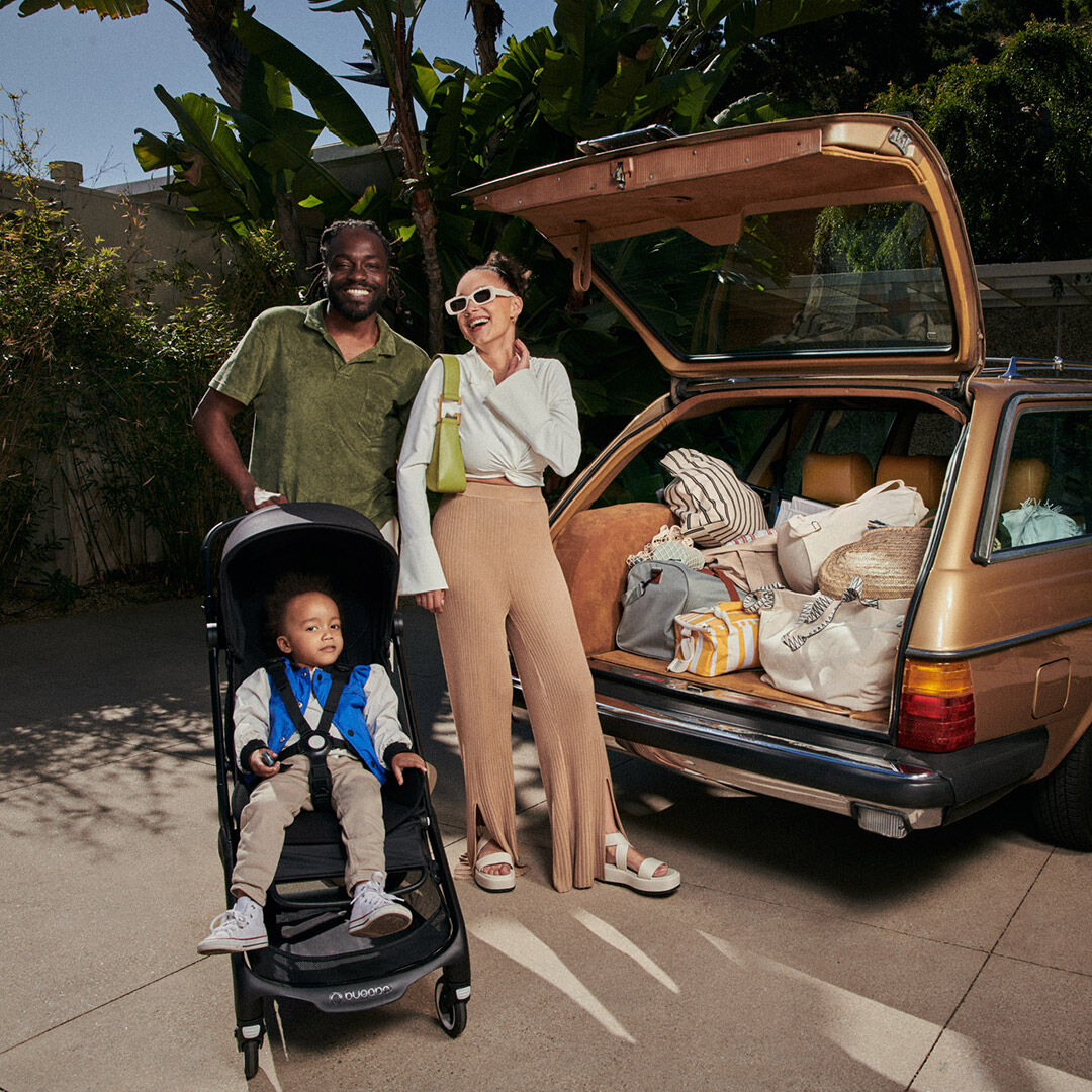 Family posing behind car