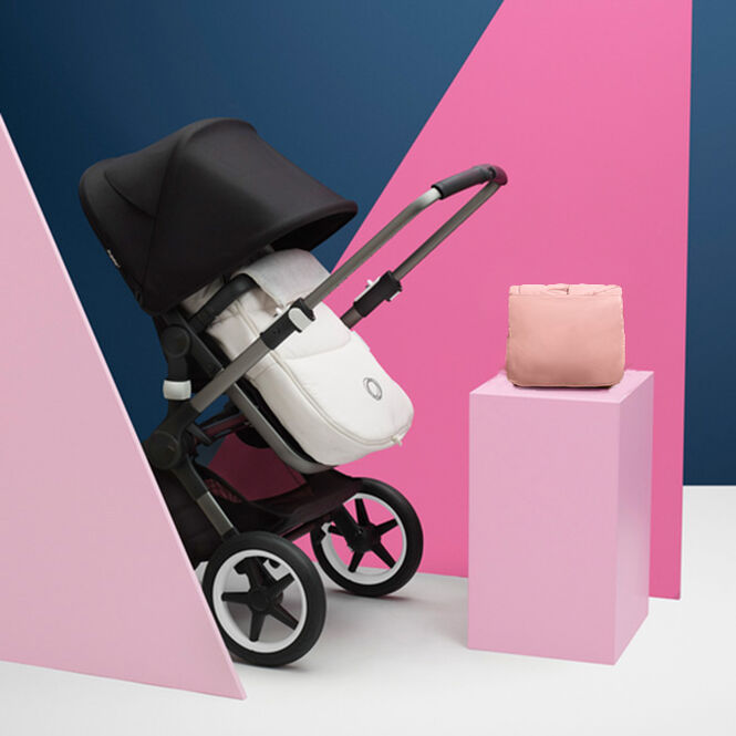 The Bugaboo footmuff on a Bugaboo stroller, next to a folded Bugaboo footmuff displayed on top of a block.