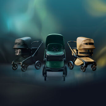 Three Bugaboo Fox 5 Noir Limited Edition strollers against a dark, ethereal background with hues of blue, yellow, and gold.