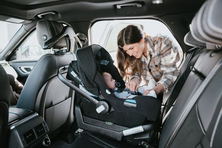 Smiling mom with baby in car seat