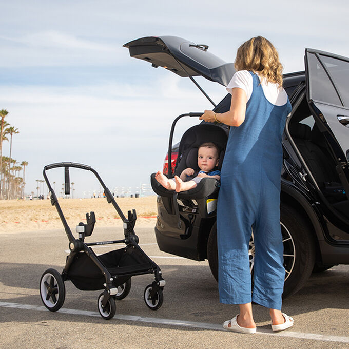 Mom transferring baby in Turtle Air by Nuna car seat from stroller to car.