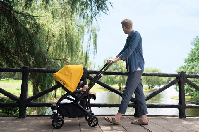 Dad crossing a bridge in a park with baby in a Bugaboo Bee 6 stroller.