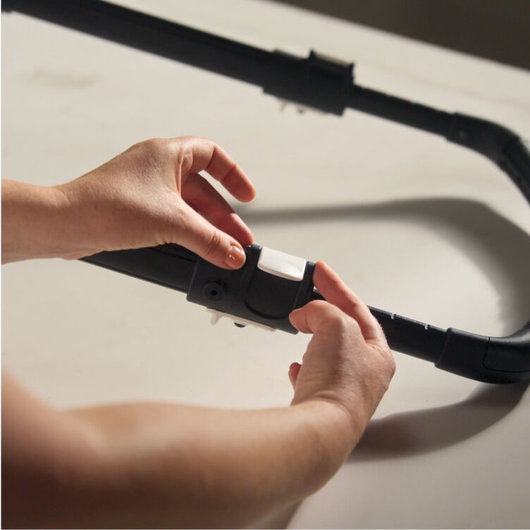 A Bugaboo expert adjusts a clip on the handlebar of a Bugaboo stroller.
