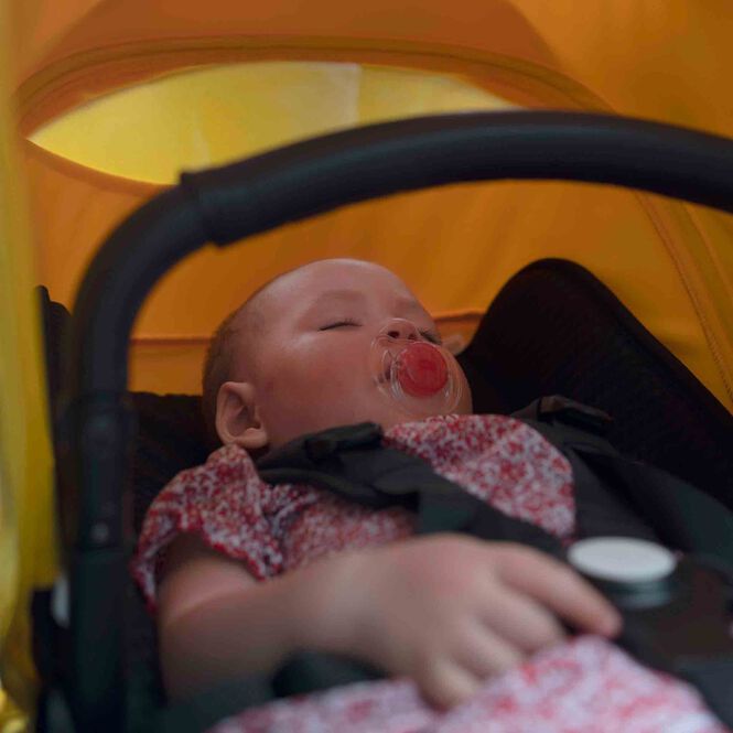 Baby snoozing peacefully inside a Bugaboo stroller.