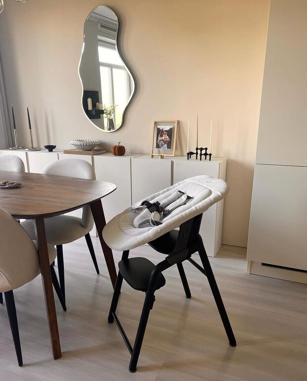 Une chaise haute Bugaboo Giraffe avec un Newborn Set se situe au milieu d'une salle à manger moderne avec du mobilier en bois et une décoration du meilleur goût.