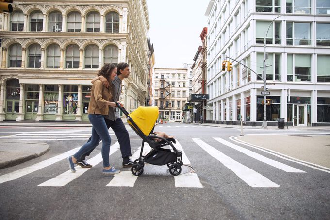 A couple crossing the street with their Bugaboo Bee 6 city stroller in the seat configuration