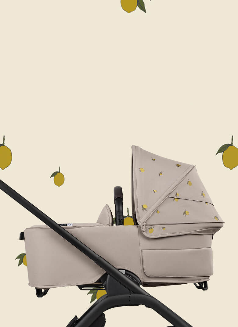 A Bugaboo Dragonfly bassinet stroller with Bugaboo X Konges Sløjd Limited Edition sun canopy, featuring Konges Sløjd's signature lemon print.