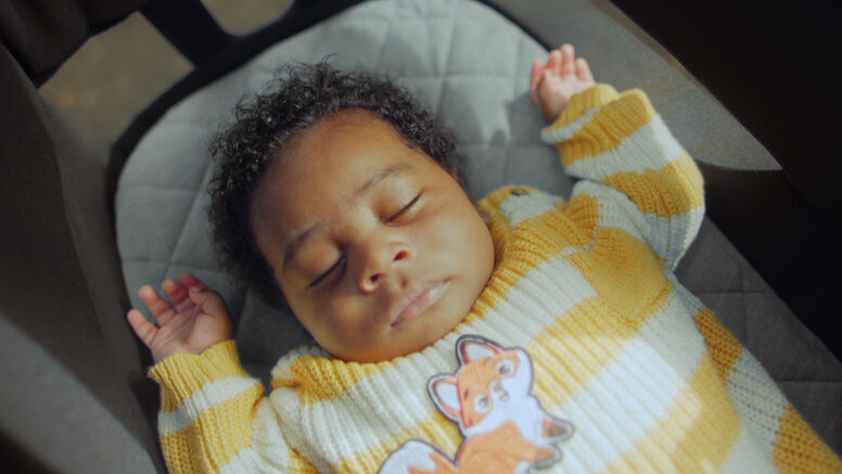 A sleeping baby wearing a yellow fox print onesie