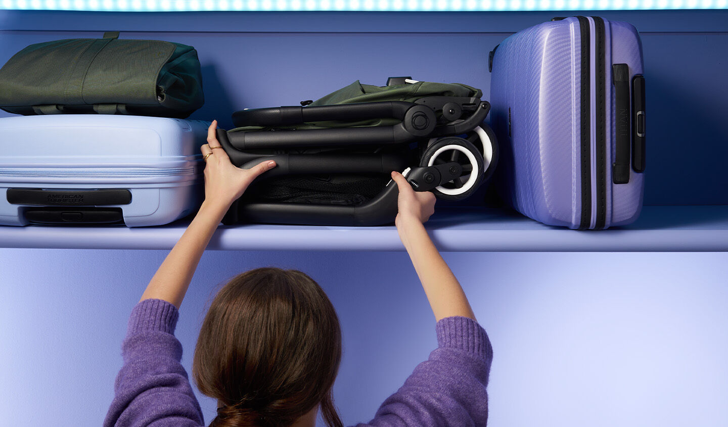 Mother storing a folded Bugaboo Butterfly neatly on the overhead luggage compartment of a plane or train.