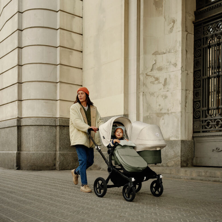 The Bugaboo Donkey 5 double stroller in forest green, with focus on the side-by-side seat and bassinet.