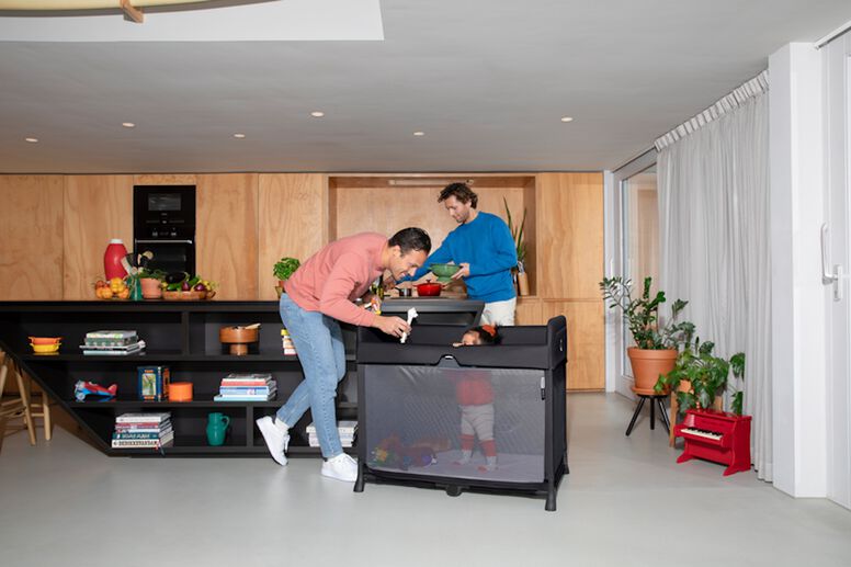 Dads cook while their baby plays in a travel play yard