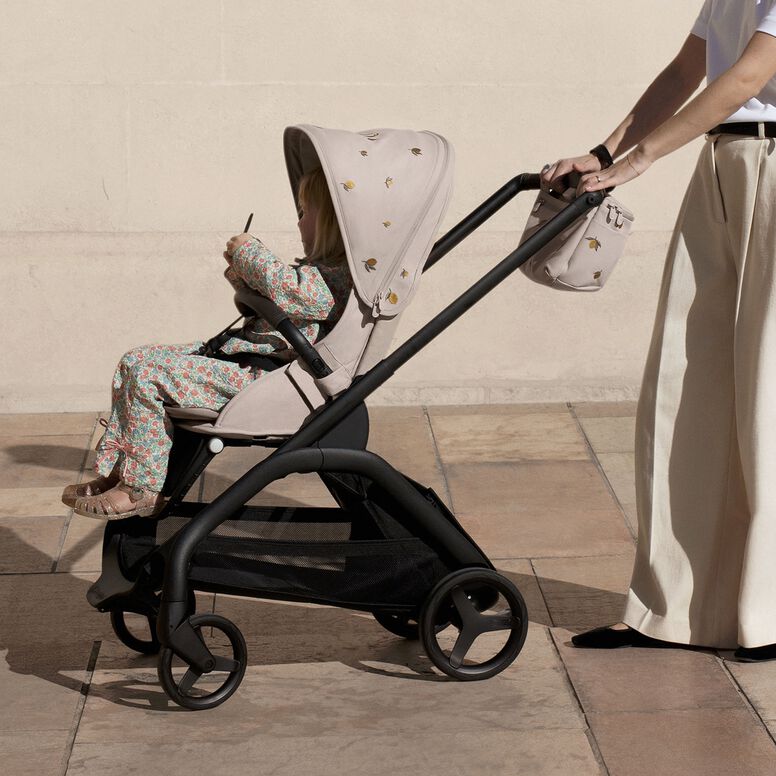 A dad and his daughter crouch in an untamed, overgrown garden. He's showing her something he's caught in his hands.