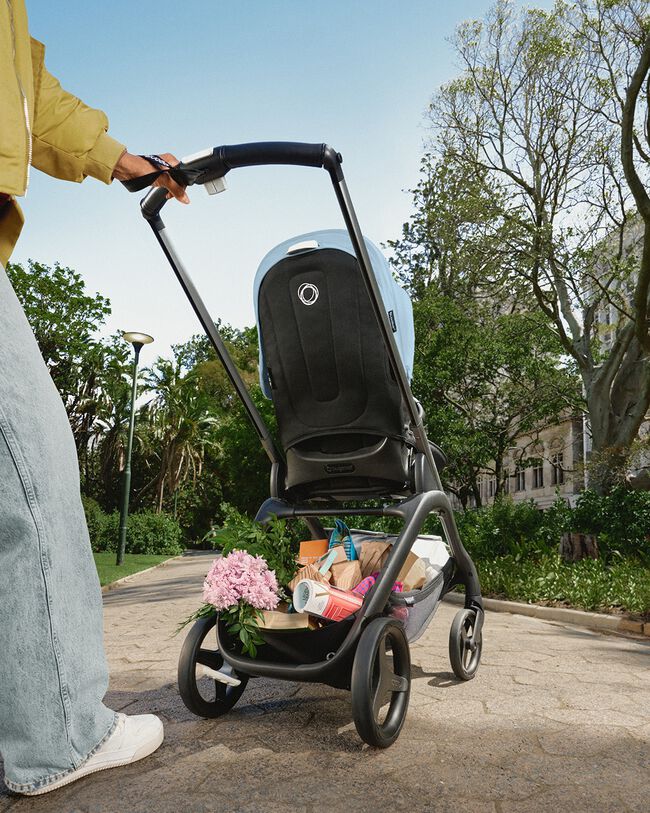 View of a Bugaboo Dragonfly pram from behind, with a fully-loaded underseat basket containing toys and groceries.