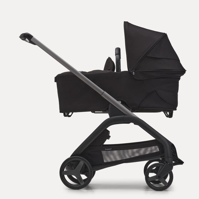 ブラックのシャーシ、ミッドナイトブラックのファブリック、ミッドナイトブラックのサンキャノピーを装着したバガブー ドラゴンフライ キャリーコットストローラーの横からの外観。 - Main Image Slide 3 of 16