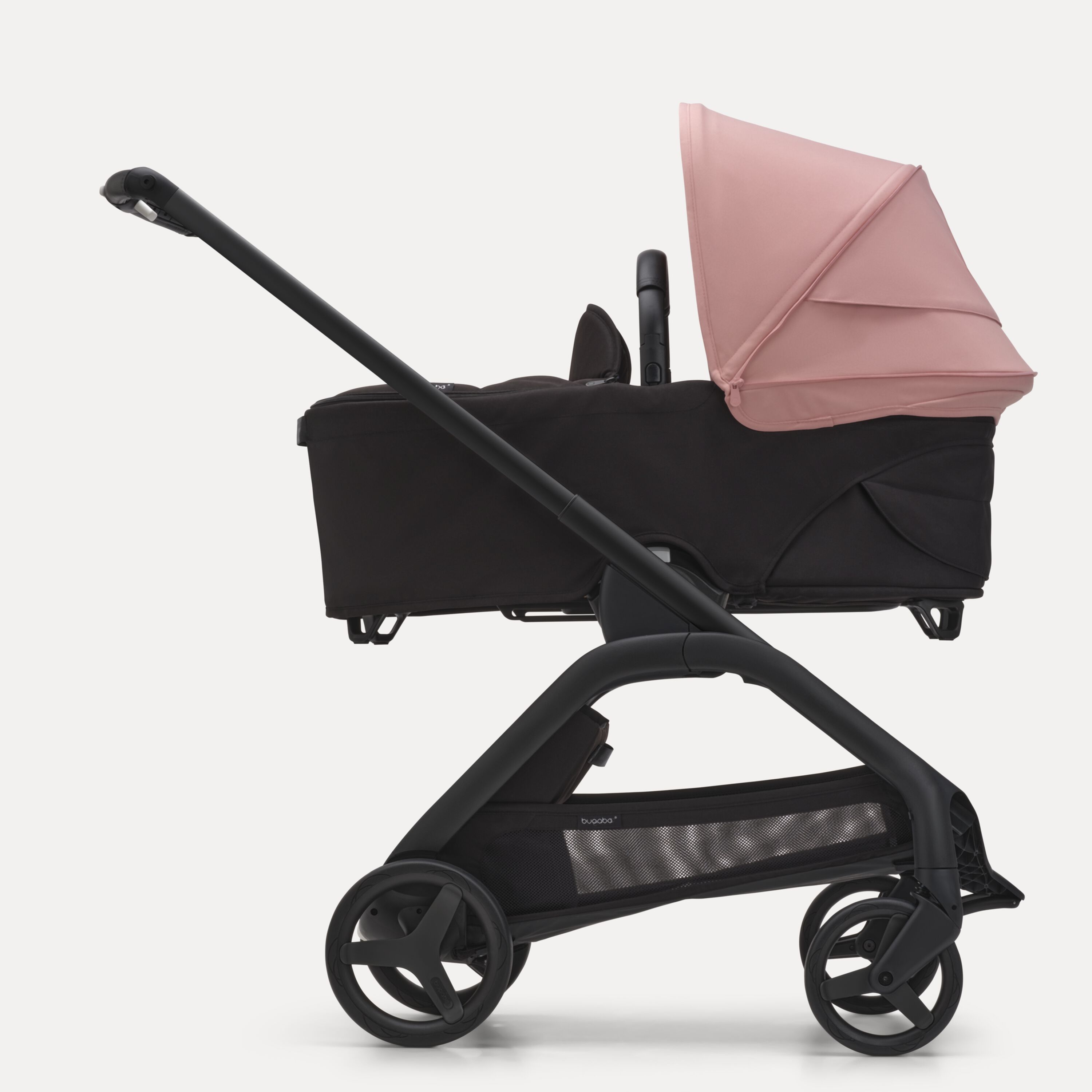 Side view of the Bugaboo Dragonfly bassinet stroller with black chassis, midnight black fabrics and morning pink sun canopy. - Main Modal Image Slide 3 of 16