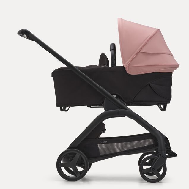 Side view of the Bugaboo Dragonfly bassinet stroller with black chassis, midnight black fabrics and morning pink sun canopy. - Main Image Slide 3 of 16