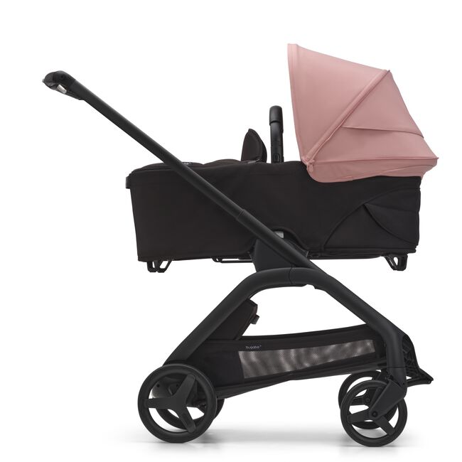 Side view of the Bugaboo Dragonfly bassinet stroller with black chassis, midnight black fabrics and morning pink sun canopy.