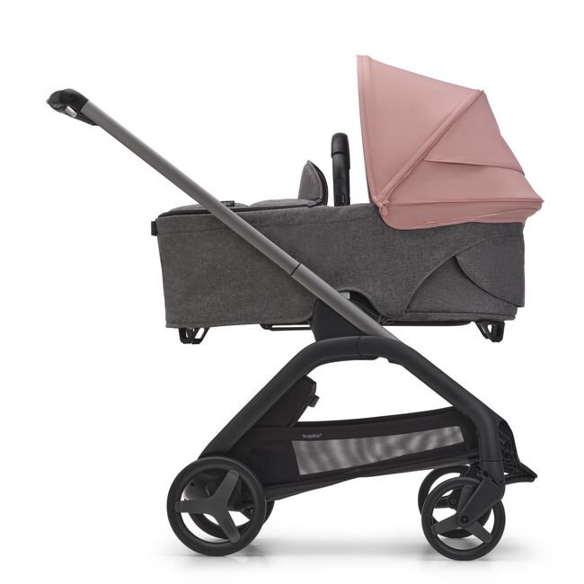 Side view of the Bugaboo Dragonfly bassinet stroller with graphite chassis, grey melange fabrics and morning pink sun canopy.