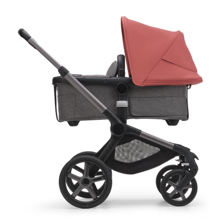 Side view of the Bugaboo Fox 5 bassinet stroller with graphite chassis, grey melange fabrics and sunrise red sun canopy. - view 2
