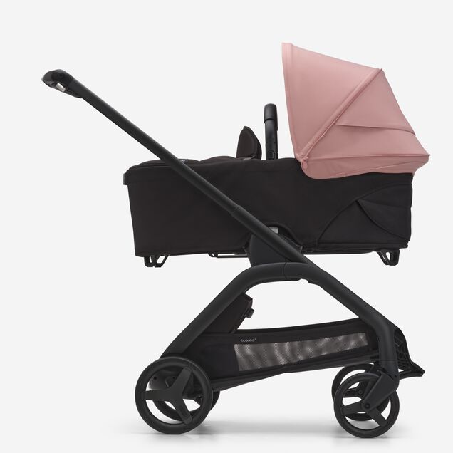 Seitenansicht des Bugaboo Dragonfly Liegewannen-Kinderwagens mit schwarzem Fahrgestell, mitternachtsschwarzem Stoff und morgenrosa Sonnendach. - Main Image Slide 3 of 16