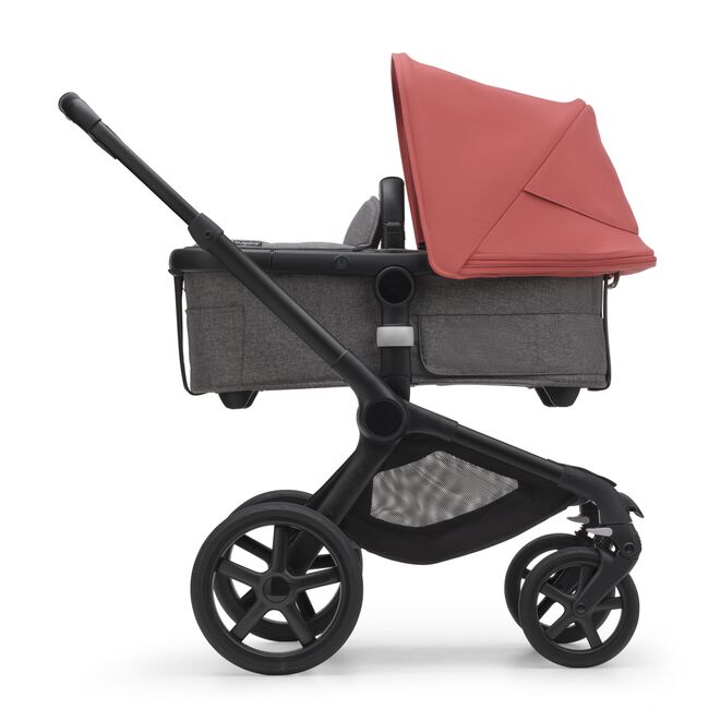 Side view of the Bugaboo Fox 5 bassinet stroller with black chassis, grey melange fabrics and sunrise red sun canopy.