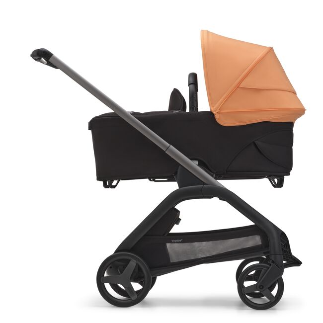 Side view of the Bugaboo Dragonfly bassinet stroller with graphite chassis, midnight black fabrics and island coral sun canopy.