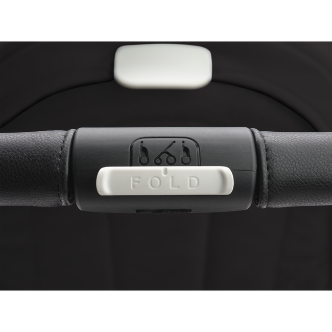 Close up on the Bugaboo Dragonfly stroller's handlebar, focusing on the big white 'Fold' button.