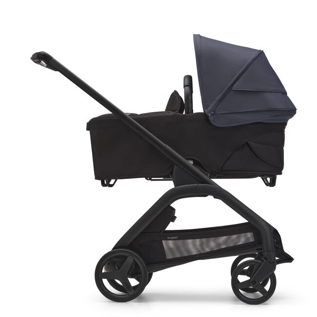 Side view of the Bugaboo Dragonfly bassinet stroller with black chassis, midnight black fabrics and stormy blue sun canopy.