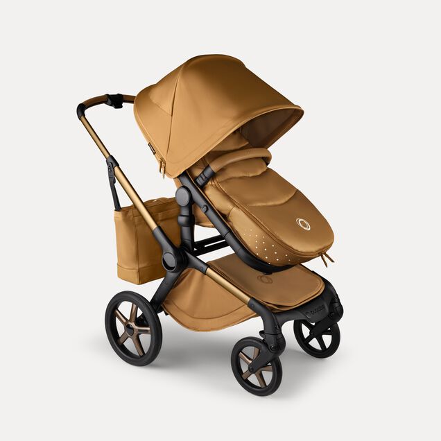 A Bugaboo Fox 5 Noir Limited Edition pushchair with a footmuff and changing bag, all in the Amber Glow colourway. - Main Image Slide 15 of 15