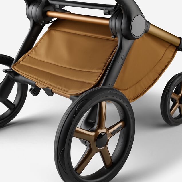 A close up of the underseat basket of the Bugaboo Fox 5 Noir Limited Edition stroller in Amber Glow. - Main Image Slide 6 of 15