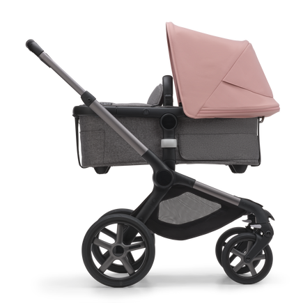 Side view of the Bugaboo Fox 5 bassinet stroller with graphite chassis, grey melange fabrics and morning pink sun canopy.