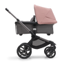 Side view of the Bugaboo Fox 5 bassinet stroller with graphite chassis, grey melange fabrics and morning pink sun canopy.