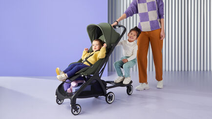 バガブー バタフライ ストローラーを押す母親とストローラーシートに座る赤ちゃん、バガブー バタフライ コンフォート ホイールボード＋に座る幼児。