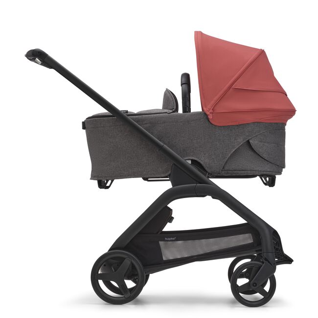 Side view of the Bugaboo Dragonfly bassinet stroller with black chassis, grey melange fabrics and sunrise red sun canopy.