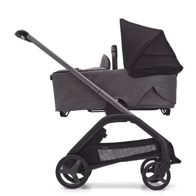 グラファイトのシャーシ、グレーメランジのファブリック、ミッドナイトブラックのサンキャノピーを装着したバガブー ドラゴンフライ キャリーコットストローラーの横からの外観。 - Main Image Slide 3 of 16