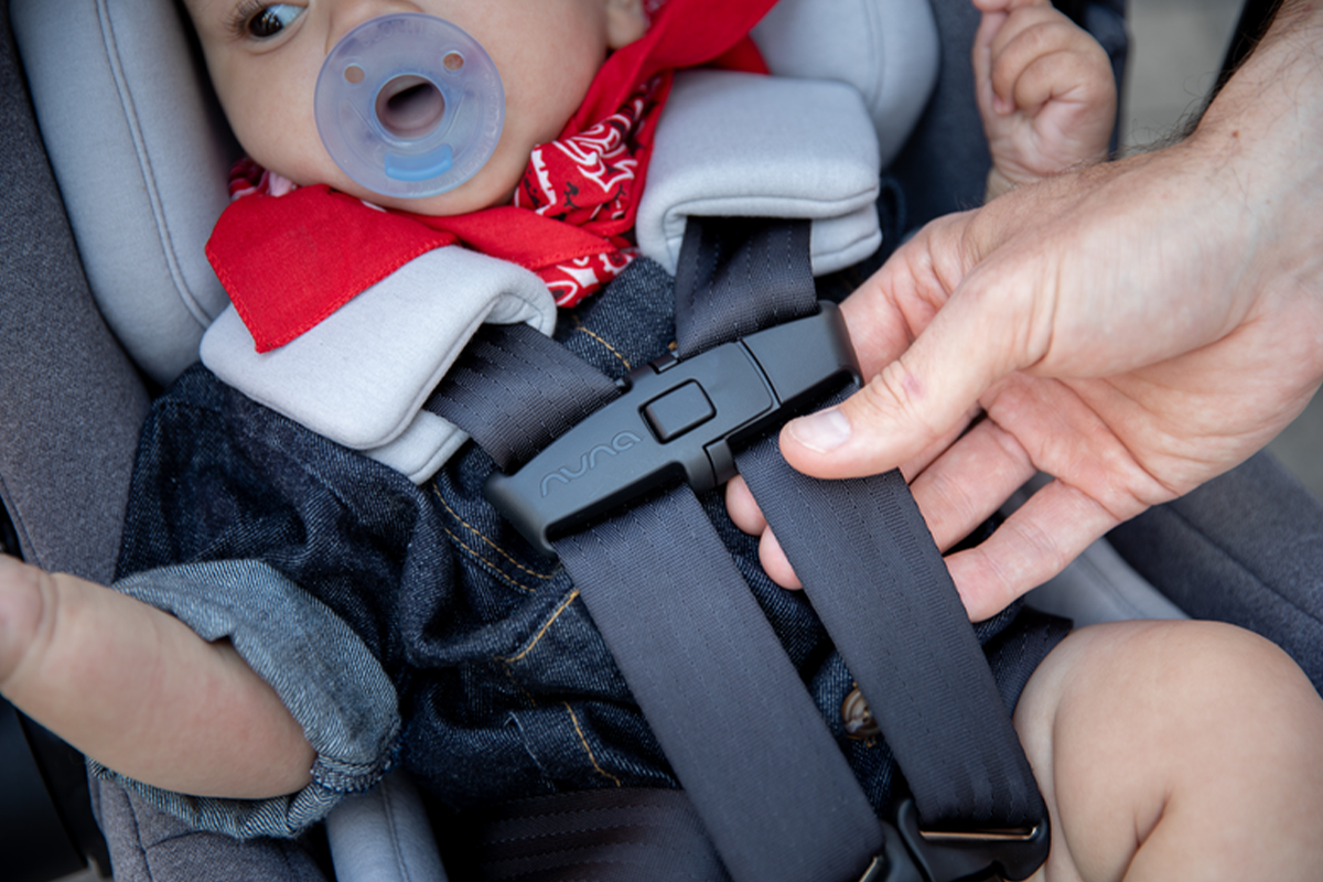 Parent handling the straps and buckles of their baby’s car seat