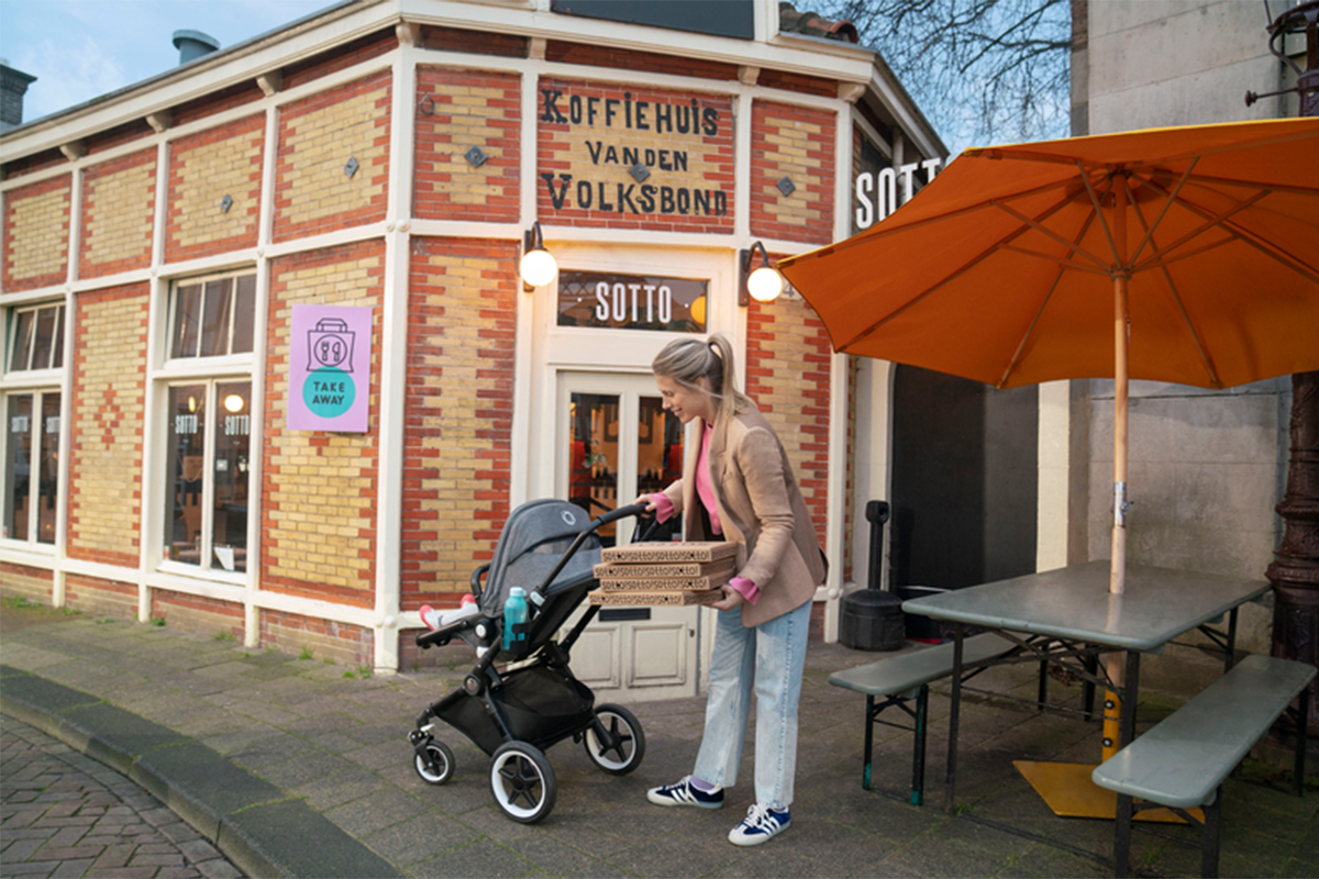 Mom picks up pizzas with her baby in a lightweight stroller