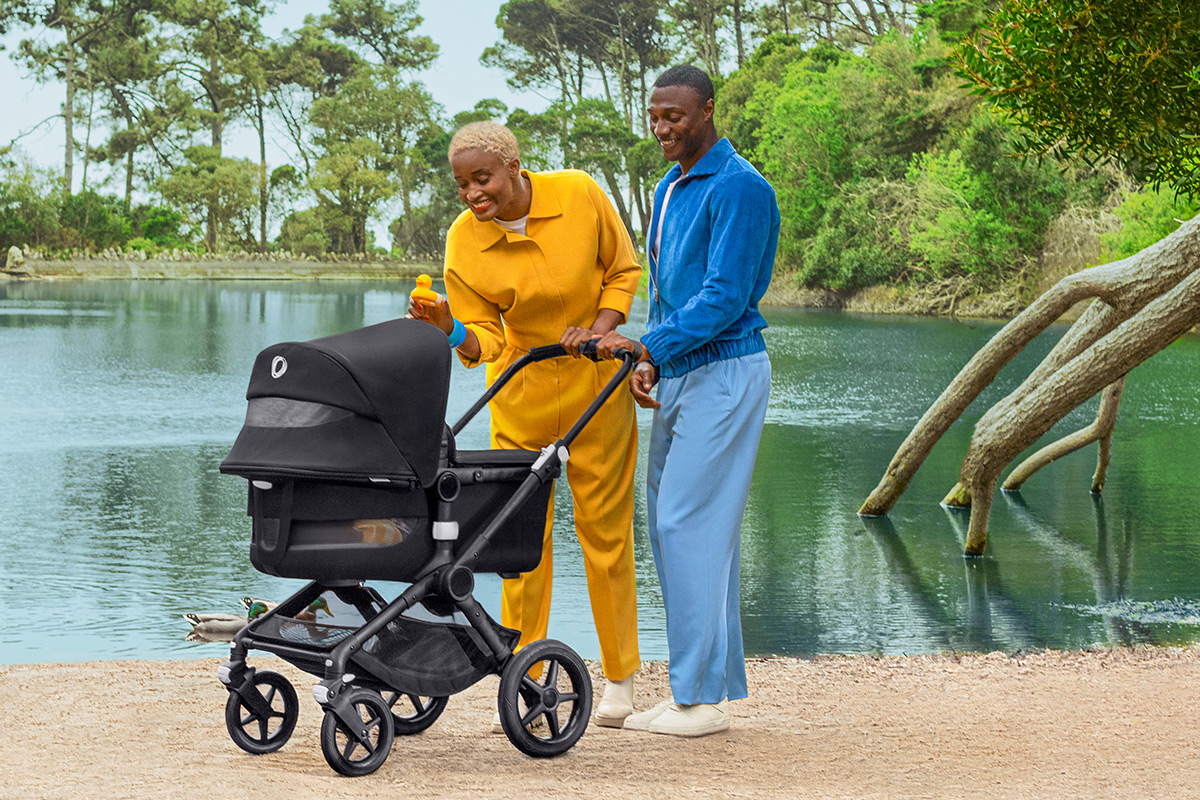 Parents in a park with her baby in a bassinet stroller