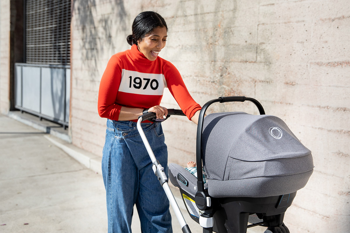 Mom smiles at her baby in a stroller while walking