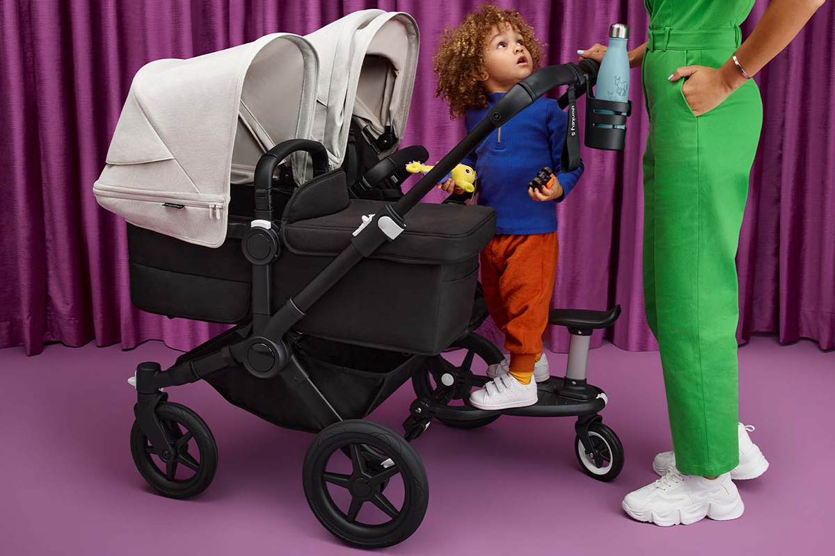 Child standing with a twin stroller