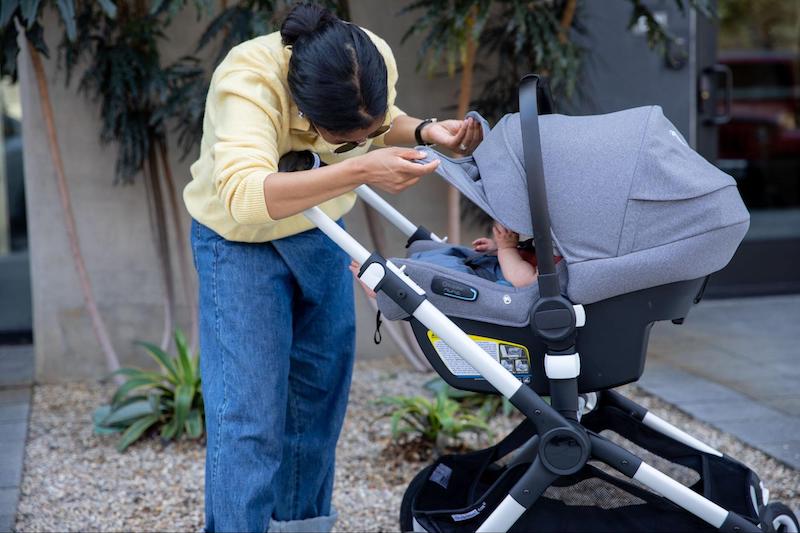 Mom peeking at her baby under a car seat stroller canopy