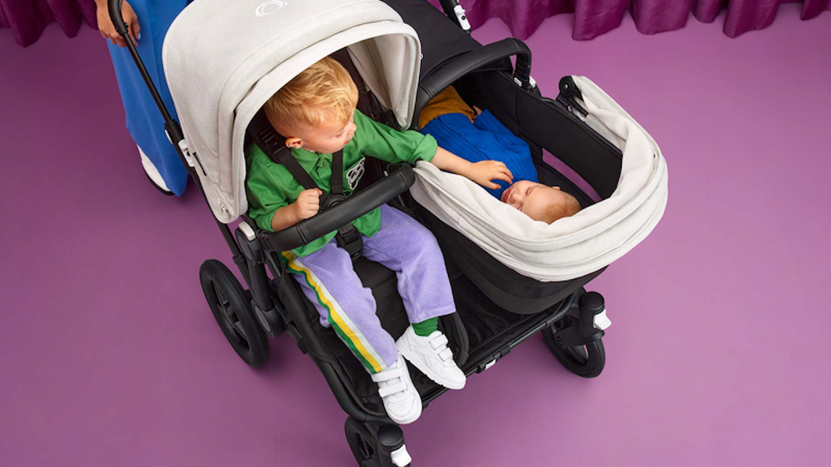 A toddler and an infant in a side-by-side double stroller