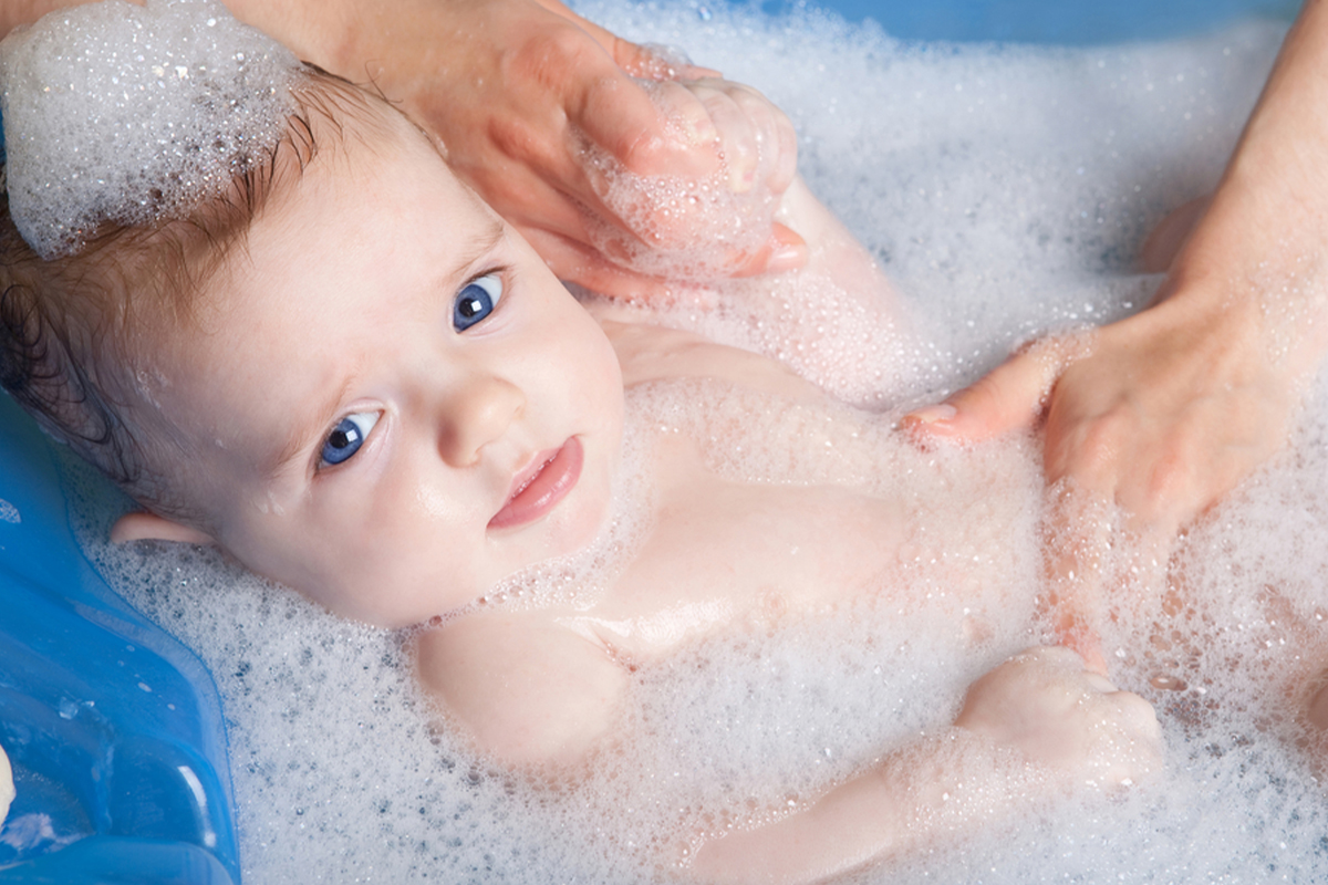 Baby covered in bubbles in a small bathtub